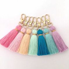 six tasselled key chains with gold hardware and pink, blue, green, yellow, and white colors