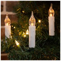 three white candles are hanging from a christmas tree