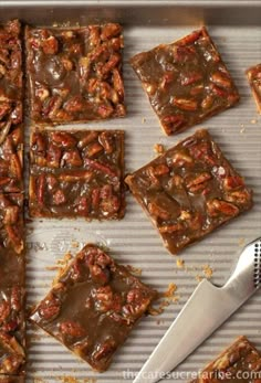 pecan bars are arranged on a baking sheet with a spatula next to them