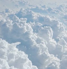 the view from an airplane window shows fluffy clouds