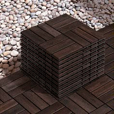 several pieces of wood stacked on top of each other in front of rocks and gravel