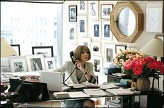 a woman sitting at a desk in front of a laptop computer talking on the phone