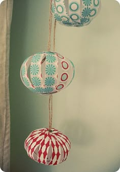 three paper lanterns hanging from strings in the shape of balls with circles and flowers on them