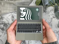 a person holding a laptop with a starbucks sticker on it