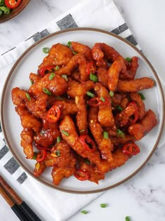 a white plate topped with chicken wings covered in sauce and garnished with green onions