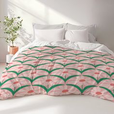 a white bed with pink and green bedspread in a room next to a potted plant