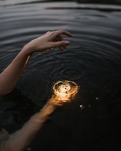 a person reaching out to the water with their hand in the air and a light shining on them