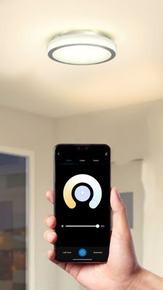 a hand holding an iphone in front of a ceiling light with the app on it