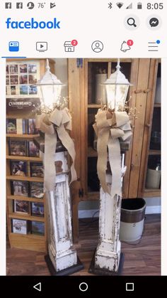 two old fashioned street lamps with bows on them are standing in front of a bookcase