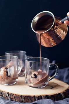 someone is pouring hot chocolate into two cups