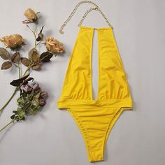 Wear confidently and turn heads with this striking this sexy yellow bathing suit. This stunning one piece swimsuit features a halter neck with metallic chain detailing that adds a touch of glamour to your look, removable soft padding cups for comfort, an alluring cut-out at the middle to enhance your curves, a high rise banded design at the waist highlighting of this swimsuit, giving it a unique and trendy look, and the high leg bikini bottom has cheeky Brazilian cut, perfect for a day of fun in Gold Backless Swimwear For Party, Gold Backless Party Swimwear, Gold Backless Swimwear For Vacation, Summer Club Bodysuit With Halter Neck, Summer Club Halter Neck Bodysuit, Summer Halter Neck Bodysuit For Club, Gold Backless Swimwear For Pool, Gold Halter Neck Swimwear For Party, Gold Lined Swimwear For The Beach