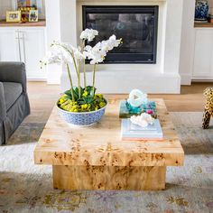 a living room with a couch, coffee table and flowers in a bowl on it