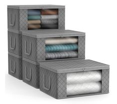 three storage boxes with folded sheets and blankets in them