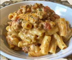 a white plate topped with pasta covered in meat and cheese sauce on top of a marble counter