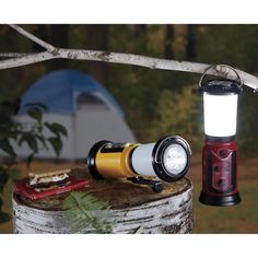 a flashlight is sitting on top of a tree stump next to a camping light and other items