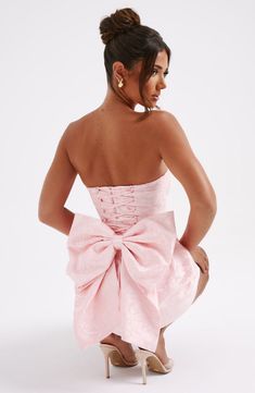 THE dress of the season has landed and you're going to be obsessed. Meet Elenora. our dreamy mini with a pretty structured skirt and waist cinching bodice. This strapless style is complete with lace up and an oversized bow to the back for perfect feminine drama.   Colour: Blush. Premium non-stretch floral jacquard. Strapless design. Waist cinching. Detachable bow. Oversized bow detail to back. Voluminous. structured skirt. Lace up to the reverse. Mini length. Model is an XS and is wearing an XS. Formal Dresses Short With Sleeves, Jr Prom Dresses Short, Grad Party Dresses, Formal Dresses Mini, Pink Short Dress, Homecoming Dresses Corset, Structured Skirt, Mini Dress With Bow, Midi Dress Wedding Guest