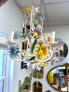 a chandelier with flowers hanging from it's sides in front of a mirror