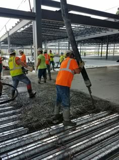 men in orange vests and safety jackets working on steel bars