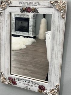 a mirror hanging on the wall in front of a fireplace with roses and leaves around it