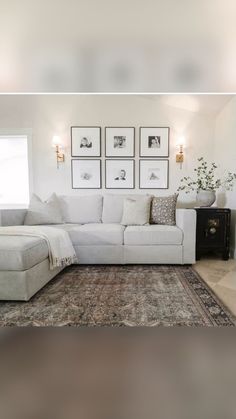 a living room with white furniture and pictures on the wall