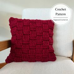 a red crochet pillow sitting on top of a white chair