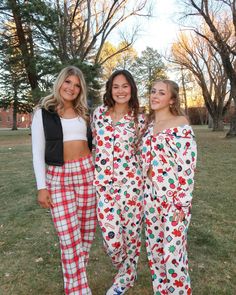 three women in matching pajama outfits posing for the camera with trees in the background