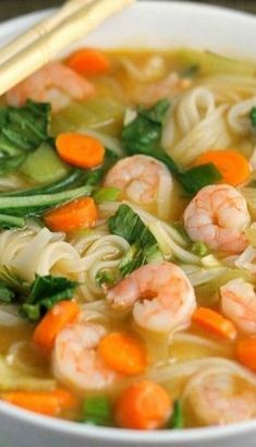 a bowl of shrimp noodle soup with carrots and spinach