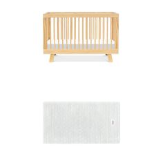 a small wooden crib next to a white rug