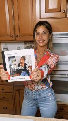 a woman holding up a magazine in her kitchen