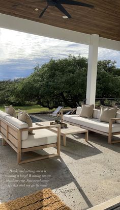 an outdoor living area with couches, tables and ceiling fan on the patio overlooking the ocean