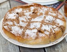 a cake sitting on top of a white plate covered in powdered sugar