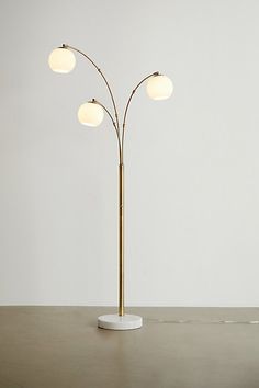 a floor lamp with three lights on top of it and a round base in the middle