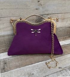 Stunning, handmade, purple velvet clutch bag with dragonfly detail. The lining is made with a beautiful fabric. Use it as a classic clutch or attach the shoulder strap to wear over your shoulder or as a crossbody. - Gold colour Chain strap (detachable) - Gold colour Kiss clasp (20.5cm) - Rhinestone dragonfly (not detachable) - H:21.5cm (handle not included) x W:29.5cm x D:5cm approximately The pattern of the lining inside of the bag may vary. But don't worry, I always make sure the lining of the Elegant Purple Pouch Shoulder Bag, Elegant Purple Clutch For Everyday Use, Elegant Purple Handheld Bag, Elegant Purple Bag Gift, Elegant Purple Evening Bag, Purple Pouch Evening Bag As Gift, Purple Rectangular Evening Bag As Gift, Elegant Purple Clutch For Daily Use, Purple Clutch Shoulder Bag For Evening