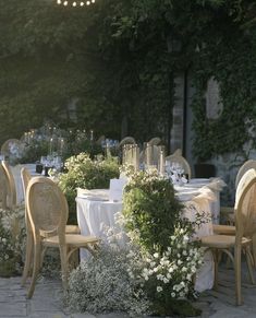 tables and chairs are set up for an outdoor dinner party with string lights strung over them