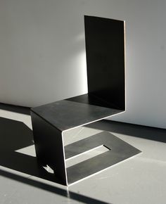 a metal sculpture sitting on top of a white floor next to a wall with light coming through it