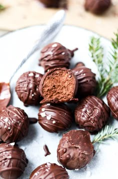 chocolate truffles on a plate with rosemary sprigs and spoon in the background