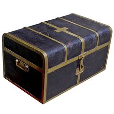 an old suitcase with gold trimmings on the top and bottom, sitting upright