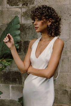 a woman in a white dress holding a large green leaf and looking off into the distance