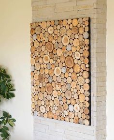 a wall made out of wood logs in front of a potted plant