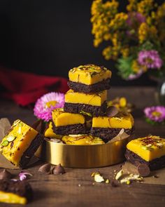 a stack of brownies with yellow frosting sitting on top of a wooden table