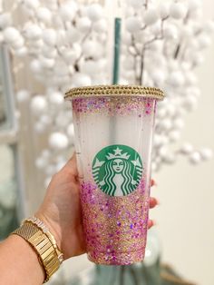 a hand holding a starbucks cup with pink and gold sprinkles