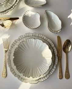 there are many plates and silverware on the table with gold forks, spoons and knives