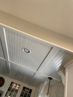 a kitchen with white cabinets and an overhead light fixture in the center of the room