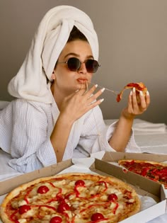 a woman in a towel is eating pizza