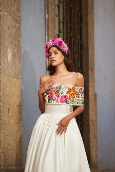 a woman in a white dress with pink flowers on her head is posing for the camera