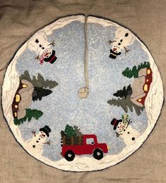 a round christmas tree skirt with snowmen and trees on the front, around a red truck