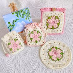 four crocheted purses are sitting on a white tablecloth next to an easel