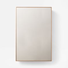 a square mirror mounted to the side of a wall above a wooden frame on a white wall