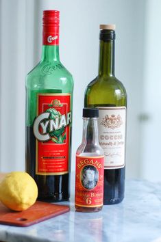 two bottles of wine, an orange and a lemon on a counter