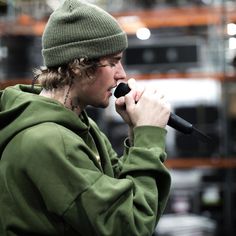 a man in a green hoodie singing into a microphone